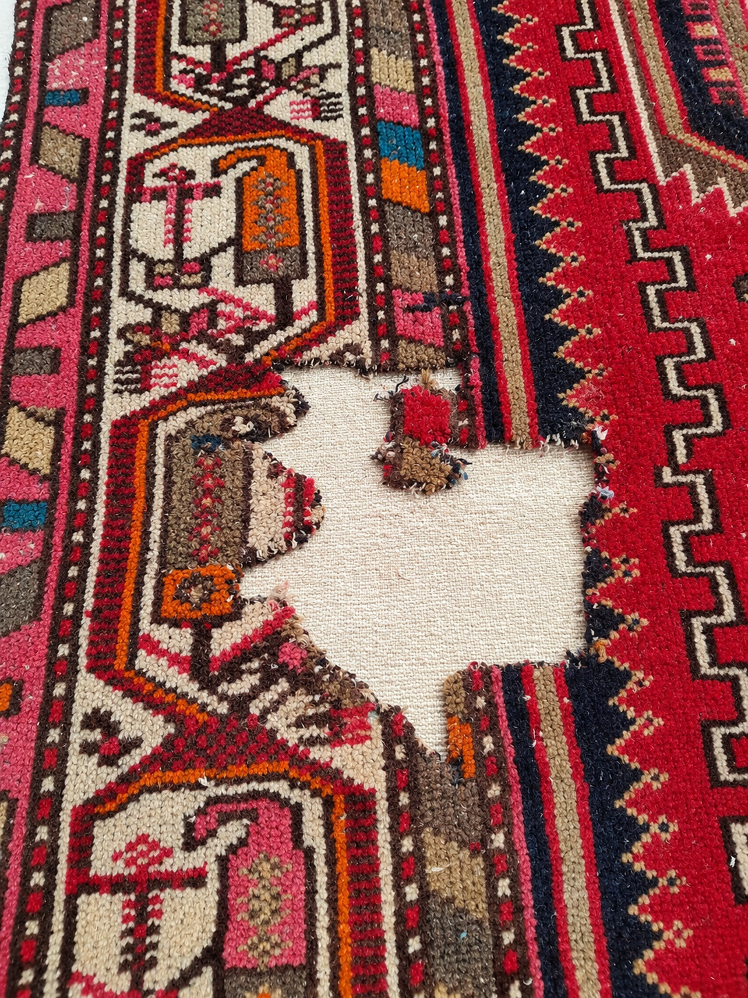 Close-up of damage on a Persian carpet before restoration